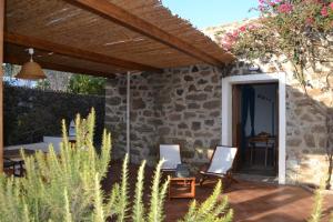 a patio with two chairs in front of a stone house at Dammuso Primavera in Pantelleria