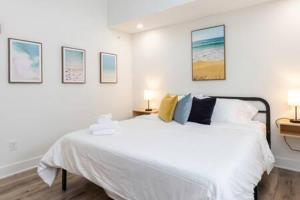 1 dormitorio con 1 cama blanca con cuadros en la pared en Ocean Lofts in the Vibe #8 - 5 min walk to beach, en Virginia Beach
