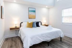 a white bedroom with a large bed with yellow pillows at Ocean Lofts in the Vibe #8 - 5 min walk to beach in Virginia Beach