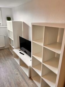 un estante de libros blanco con un televisor. en Mc Monti Gießen - Lich, 70qm, Zentral, NETFLIX, en Lich