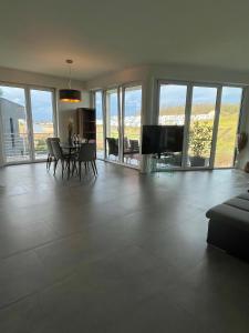 - un salon avec une table, des chaises et des fenêtres dans l'établissement Luxus Neubauwohnung mit Blick auf den Phönix-See, à Dortmund