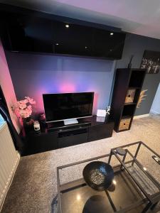 a living room with a flat screen tv and a chair at Ty Daisy, Gilwern in Gilwern