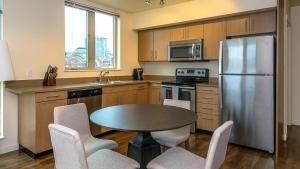 a kitchen with a table and a stainless steel refrigerator at Landing Modern Apartment with Amazing Amenities (ID8493X21) in Tacoma