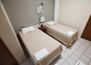 2 łóżka w małym pokoju z lustrem w obiekcie SERRA AZUL PLAZA HOTEL w mieście Barra do Garças