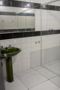 W łazience znajduje się zielona umywalka i przeszklony prysznic. w obiekcie HOTEL VILAS DOS MONTES w mieście Montes Claros