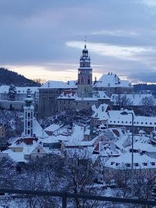 a city covered in snow with a clock tower at Penzion Albatros in Český Krumlov
