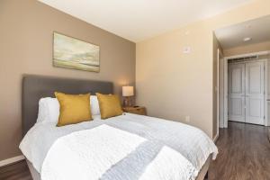 ein Schlafzimmer mit einem großen weißen Bett mit gelben Kissen in der Unterkunft Landing Modern Apartment with Amazing Amenities (ID1148) in Arlington