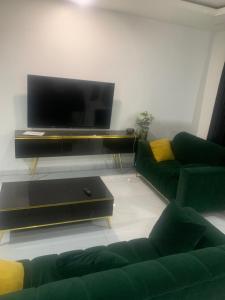 a living room with two green couches and a flat screen tv at GT Guesthouse in Warri