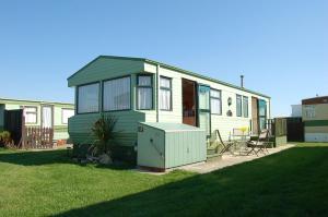 una casetta verde e bianca in un cortile di Caravan 252 Bryn Y Mor Beach Side Park a Tywyn