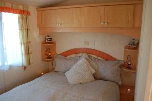 una camera con letto e testiera in legno di Caravan 252 Bryn Y Mor Beach Side Park a Tywyn