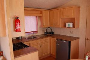 una piccola cucina con armadi in legno e un estintore di Caravan 252 Bryn Y Mor Beach Side Park a Tywyn