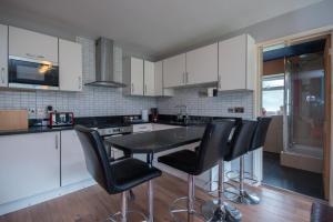 a kitchen with black counter chairs and white cabinets at Fairwinds in Sandbanks