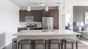 uma cozinha com uma grande ilha branca com bancos de bar em Landing Modern Apartment with Amazing Amenities (ID1209X830) em West Dundee