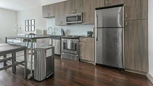 una cocina con electrodomésticos de acero inoxidable y armarios de madera en Landing Modern Apartment with Amazing Amenities (ID1401), en Alexandria