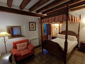 a bedroom with a canopy bed and a red chair at Hostal Posada La Panadera in Sepúlveda