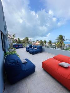 a balcony with blue and red couches and palm trees at Liiv Hub in Natal