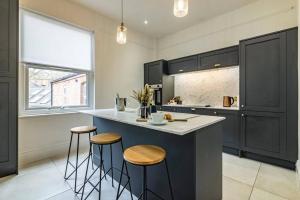 a kitchen with black cabinets and a counter with stools at Affordable luxurious 3 bedroom 3 bathroom house great for contractors and large groups within 1 mile to City Centre with free parking in Nottingham