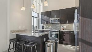 a kitchen with stainless steel appliances and bar stools at Landing Modern Apartment with Amazing Amenities (ID6802X67) in Baltimore