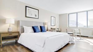 a white bedroom with a large bed with blue pillows at Landing Modern Apartment with Amazing Amenities (ID7280X77) in Arlington