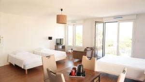 ein Wohnzimmer mit 2 Betten und einem Tisch in der Unterkunft Zenao Appart'Hotel in Nevers