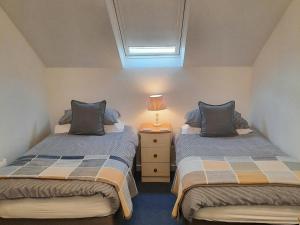 a bedroom with two beds and a lamp on a night stand at Cwmwdig Cwtch (3 minutes drive to Abereiddy bay!) in Haverfordwest