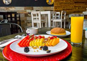 un plato de frutas y hortalizas en una mesa con zumo de naranja en Cadillac Hotel Boutique, en Ciudad de México