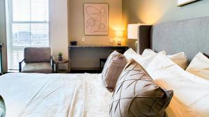 um quarto com uma cama branca e uma cadeira em Landing Modern Apartment with Amazing Amenities (ID3107X26) em Denver
