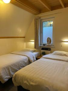 twee bedden in een kamer met een raam bij Bungalows in het Holt in Gramsbergen