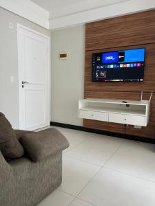 ein Wohnzimmer mit einem Sofa und einem TV an der Wand in der Unterkunft Ocean flat com vista pro mar 404 in Vila Velha