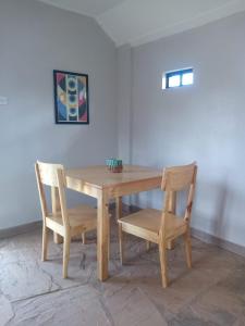 a wooden table with two chairs and a table and a table and chairs at KIJIJI VILLAGE in Emali