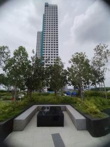 een bankje in een park met een hoog gebouw bij Family Fun Staycation @ Thelima Suite in Kajang