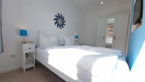a white bedroom with a large bed with white sheets at Urlaub am Rosengarten in Güstrow