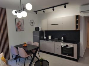 a kitchen with white cabinets and a table and chairs at LUX ARENA RESIDENCE EMA in Pula