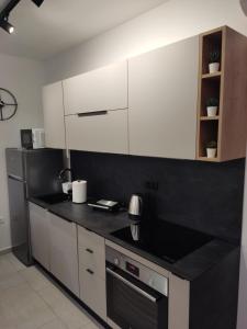 a kitchen with white cabinets and a black counter top at LUX ARENA RESIDENCE EMA in Pula +25 photos