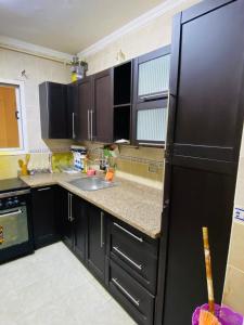 - une cuisine avec des armoires noires et un réfrigérateur noir dans l'établissement Madinaty - مدينتي, à Madinaty