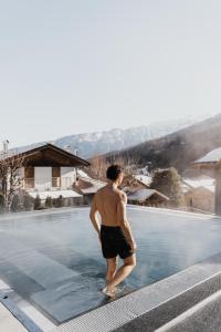 梅扎納的住宿－Hotel Ravelli Luxury Spa，站在游泳池的水面上的男人