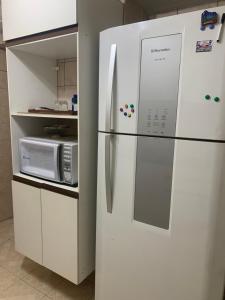 einen weißen Kühlschrank in einer Küche mit Mikrowelle in der Unterkunft Apt para 3 pessoas no centro do Recife in Recife