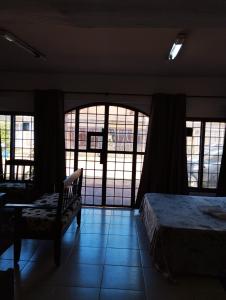 a bedroom with a bed and a chair and windows at Mangoty Apartamento in Luque