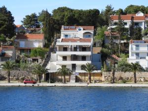 a white building next to a body of water at Moenia Apartments in Milna