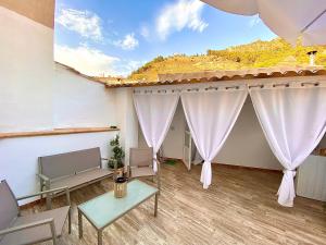 Habitación con cortinas blancas, mesa y sillas. en Casa La Romera, en Cazorla