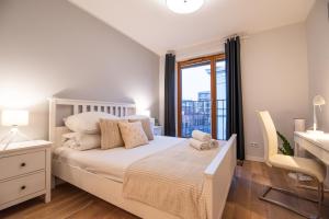 a white bedroom with a bed and a window at City Lights Apartments in Kraków