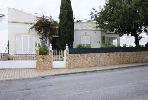una casa bianca con una recinzione in pietra accanto a una strada di Alcaria Pool House ad Altura