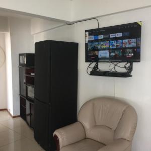 sala de estar con silla y TV de pantalla plana en DEPTO 3 AMB- Ventanales al mar INOLVIDABLES en Mar del Plata