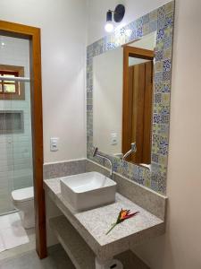 a bathroom with a sink and a mirror and a toilet at Pousada Mãe Natureza in Pirenópolis