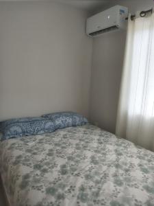 a small bedroom with a bed with a flowered blanket at Casa Completa com 2 Quartos no Centro in Pomerode