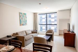 a living room with a couch and a tv at Athenas Suites By BnbHost in Salvador