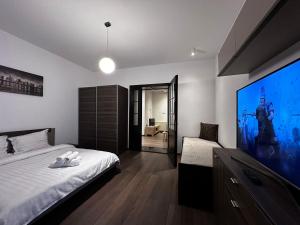 a bedroom with a large flat screen tv and a bed at elisio - Pani Nani Apartment in Braşov +8 photos