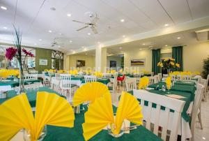 une salle à manger avec des tables et des chaises vertes et jaunes dans l'établissement Hotel Locarno, à Cattolica