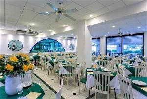 une salle à manger avec des tables vertes et des chaises blanches dans l'établissement Hotel Locarno, à Cattolica