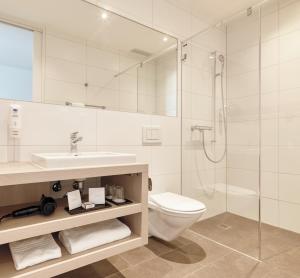 a bathroom with a toilet and a sink and a shower at Hotel Eastside (free parking garage) in St. Gallen